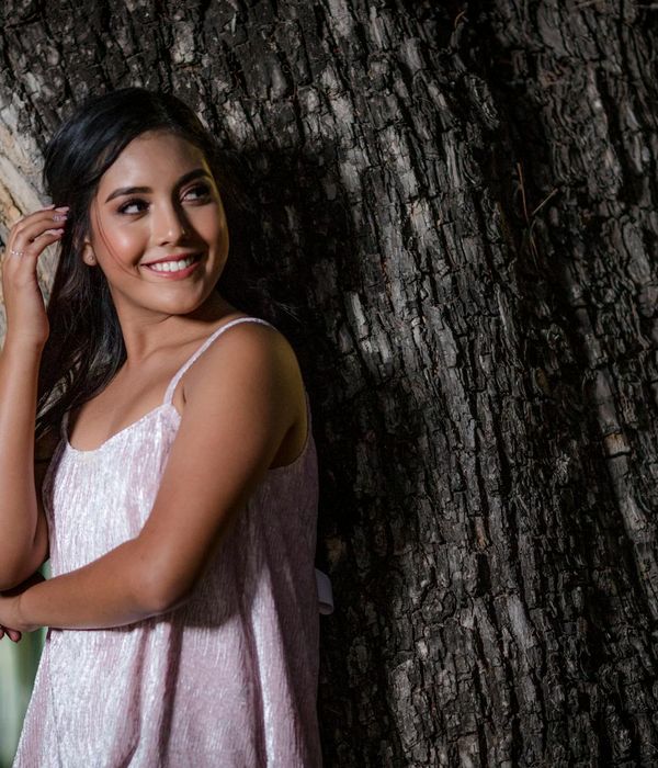Woman performing a gentle yoga pose in a dark, calm environment.